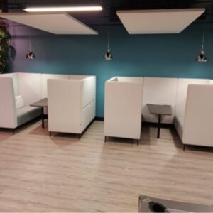 Lismark acoustic high-back booth seating in white and grey, arranged in two sets with small dark tables, set against a teal wall with a vertical plant wall feature and pendant lights.